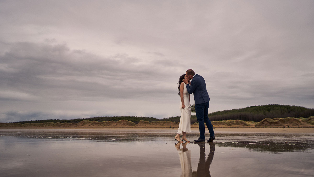 Bride and groom kissing on a beach in anglesey