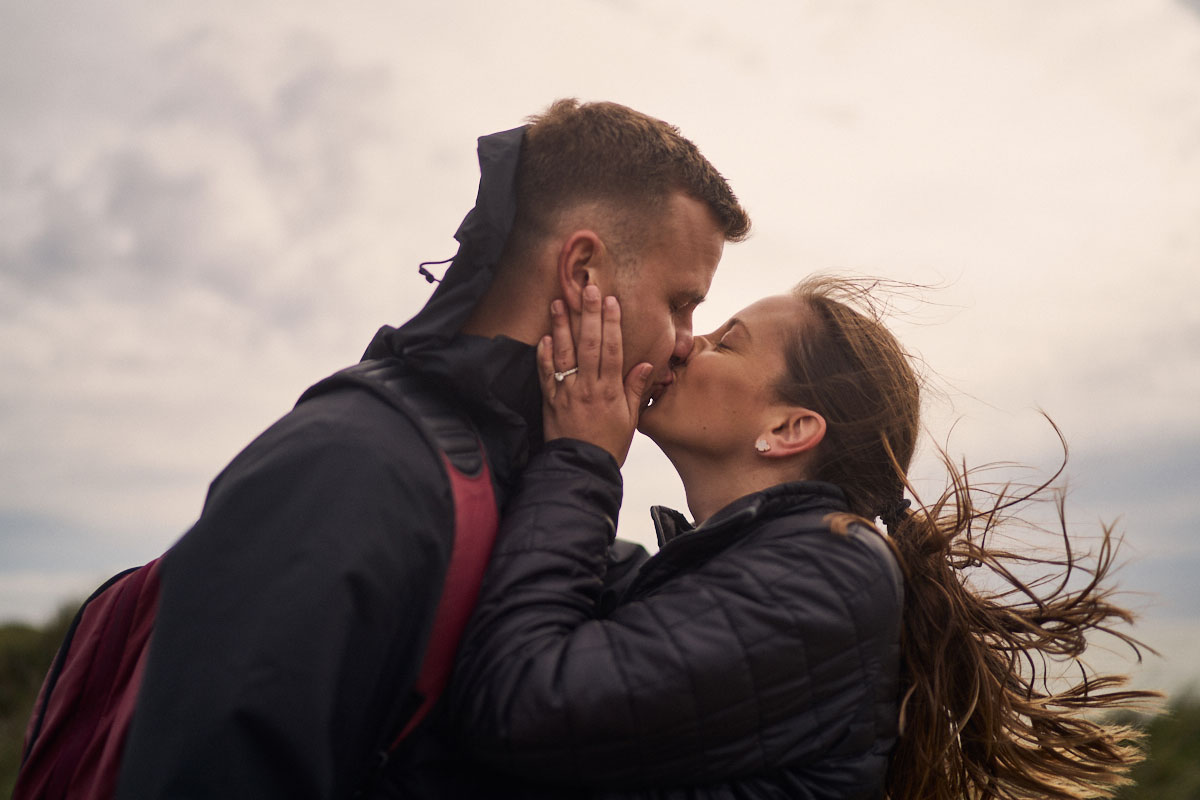 newly engaged couple kissing on Llanddwyn Island Beach