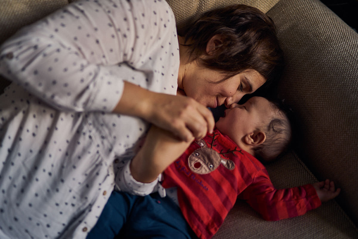 mother snuggling with her toddler on the sofa