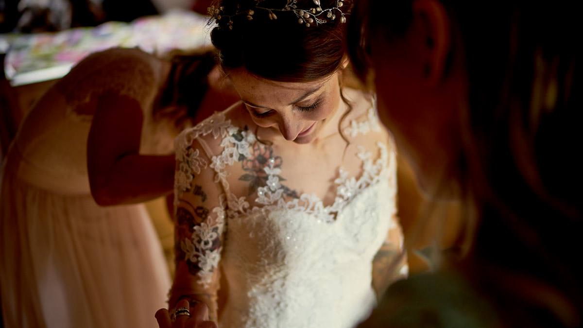 Tattooed bride getting her dress on
