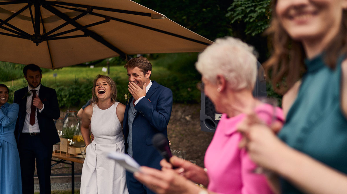 bride and groom laughing during outdoor speeches