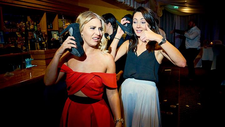 Two drunk wedding guests using their high heels as mobile phones