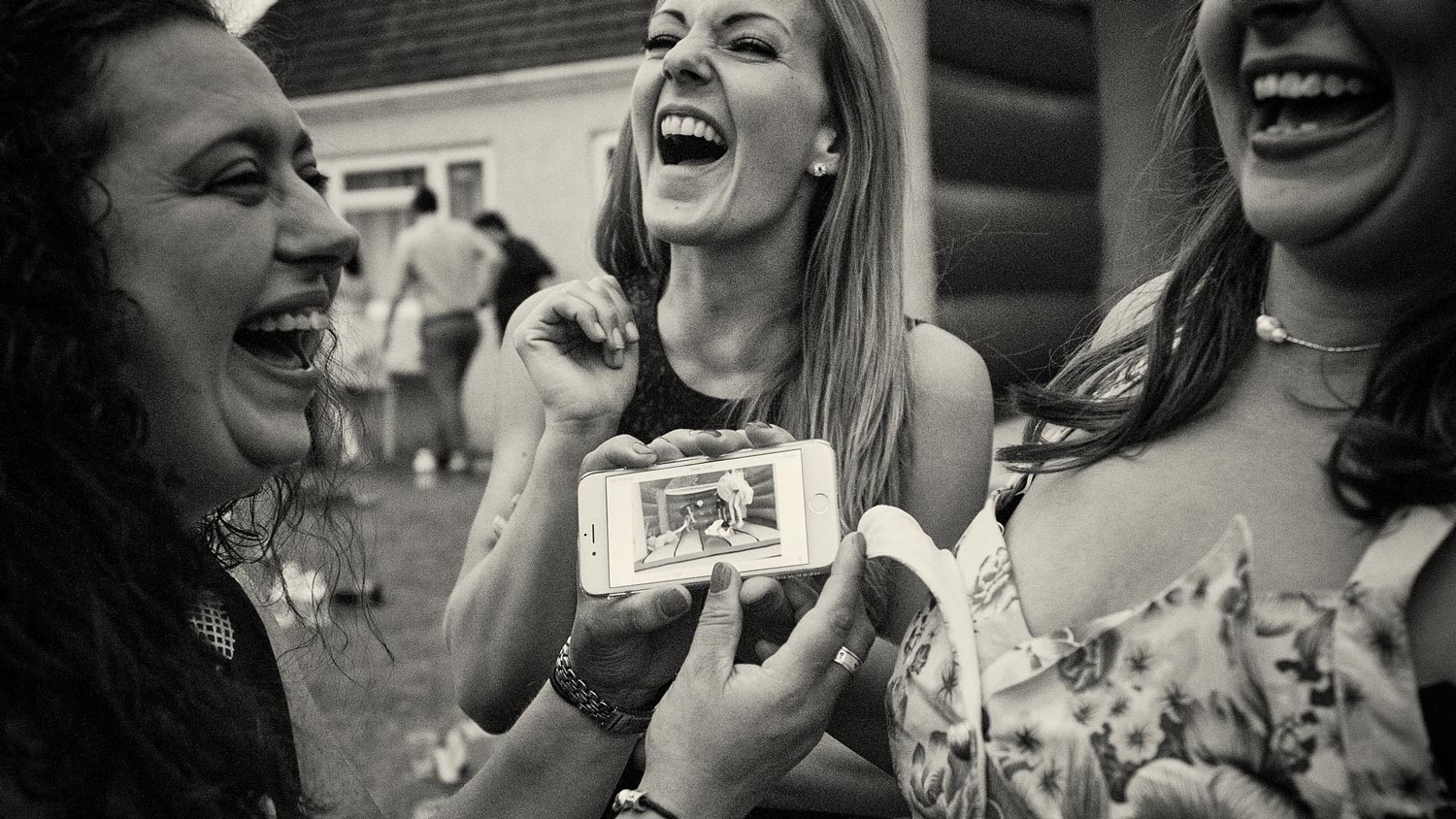 Wedding guests laughing at photo on phone
