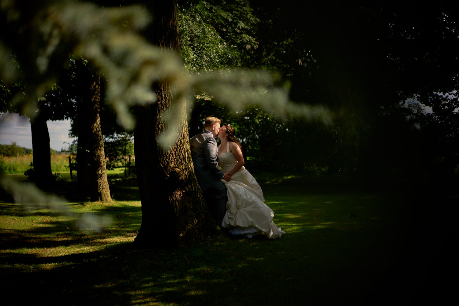 bride and groom kissing under a tree at Crabwall Manor