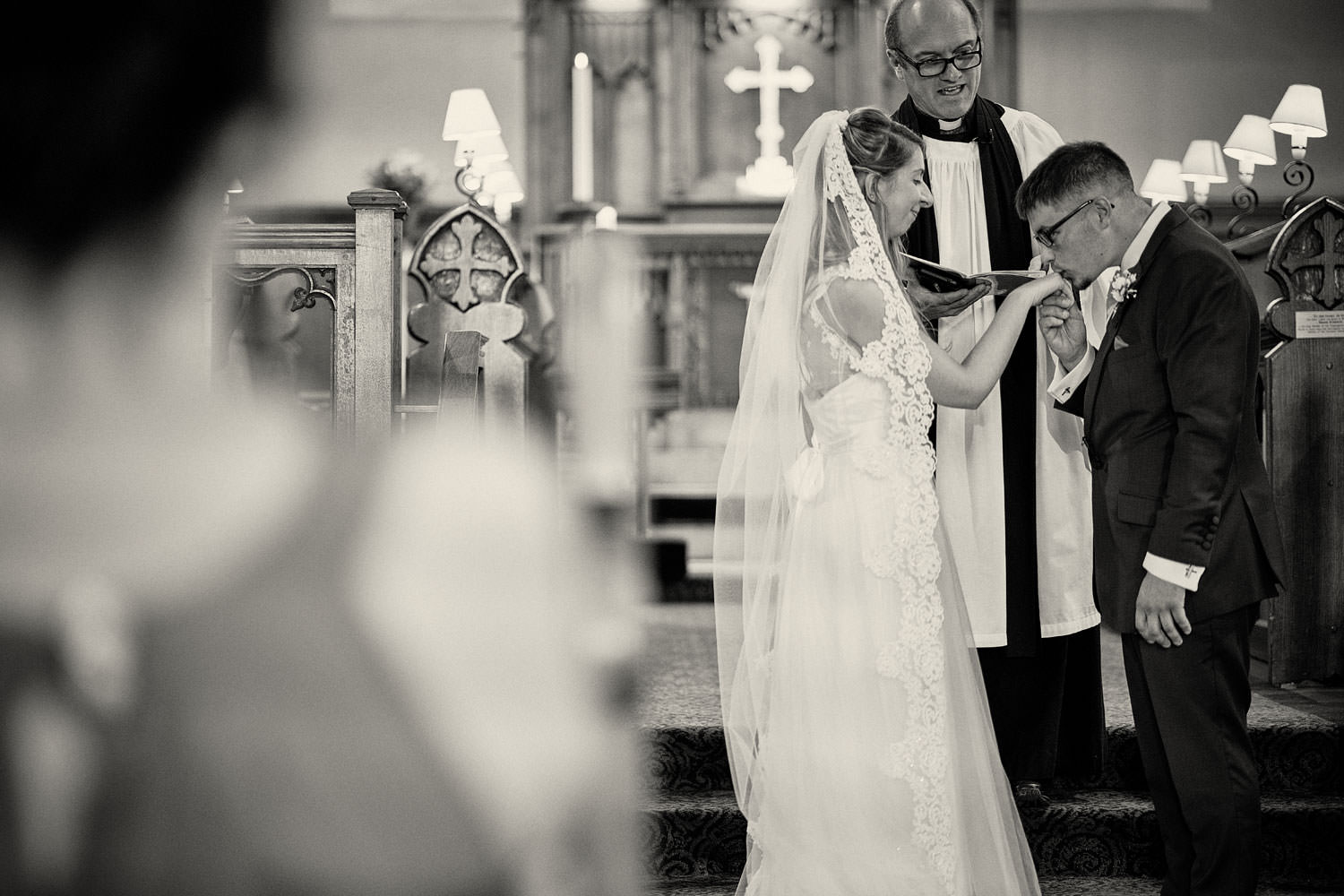 groom kissing brides hand in church