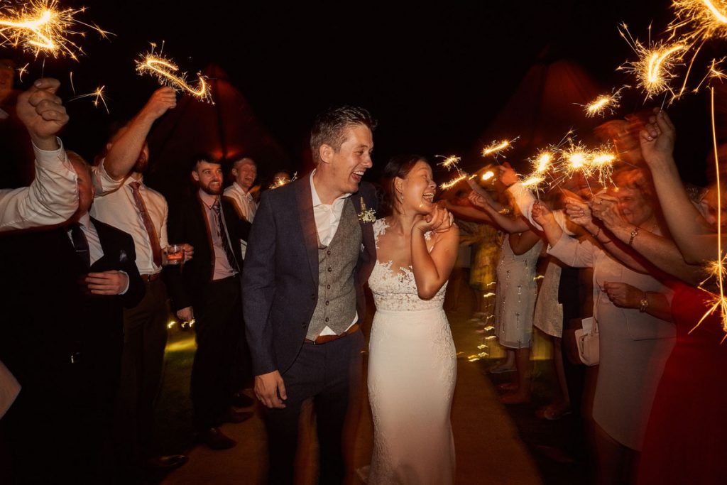 Bride & Groom leaving the tipi while guests wave sparklers