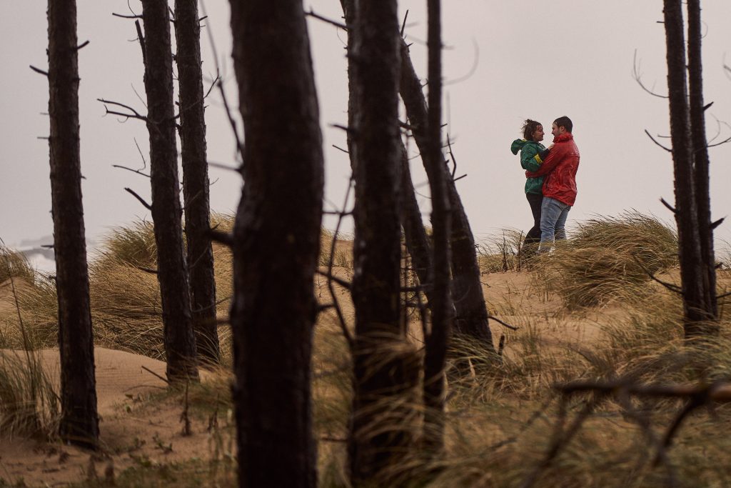 couple embrace each other at the top of the sand dunes at Llanddwyn Island