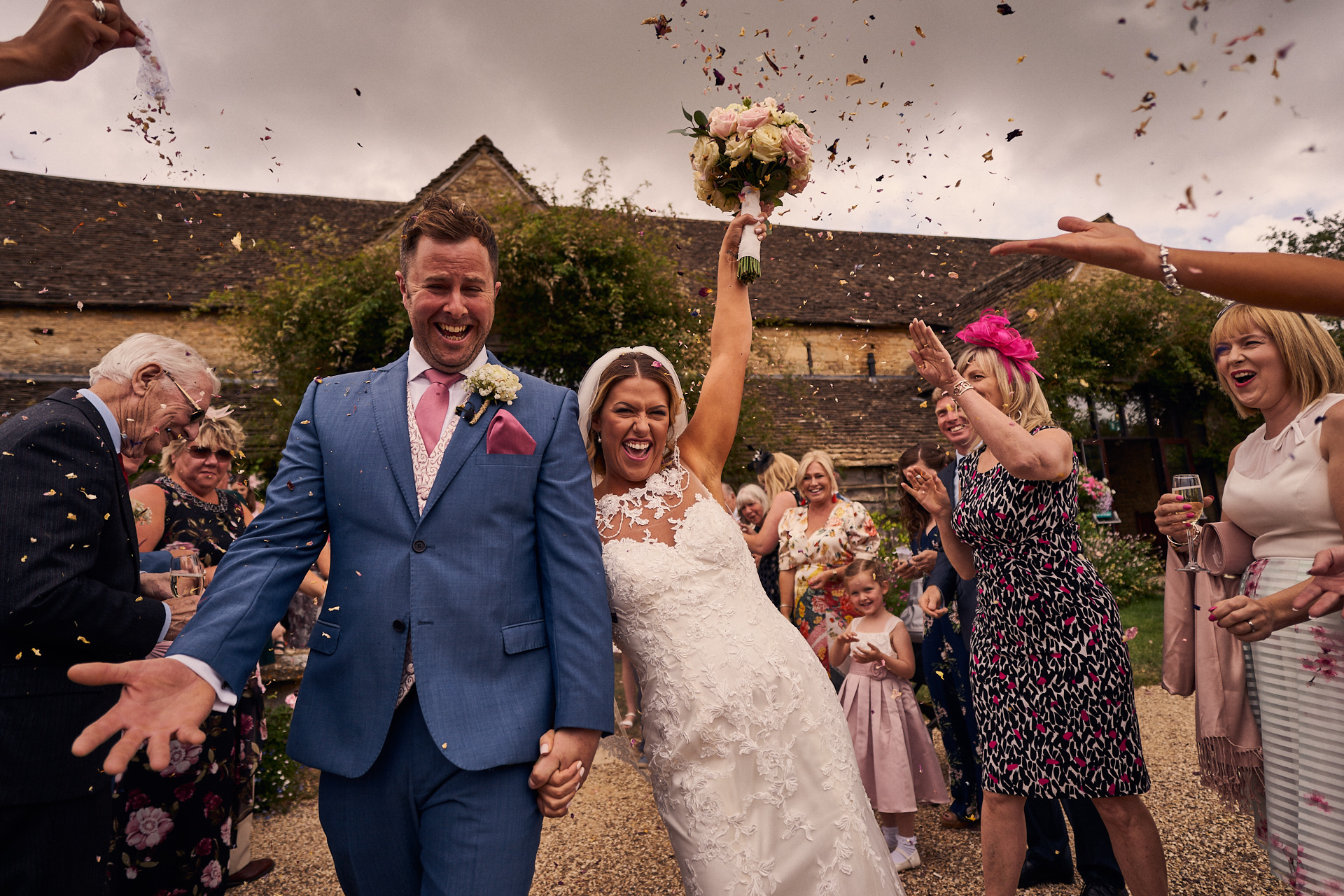 Confetti being thrown over bride and groom outside of The great tythe barn wedding venue