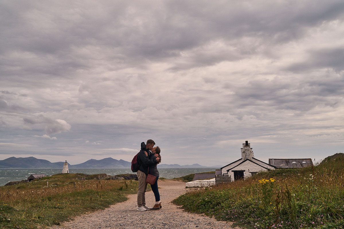 couple hugging by the pilots cottages on Llanddwyn Island 