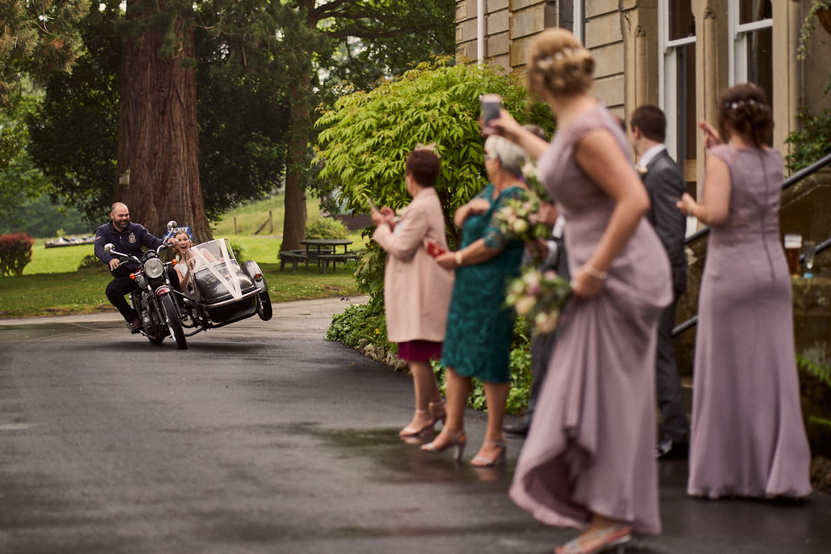 Bride doing a wheelie in a motorbike with side car - great alternative wedding day transport