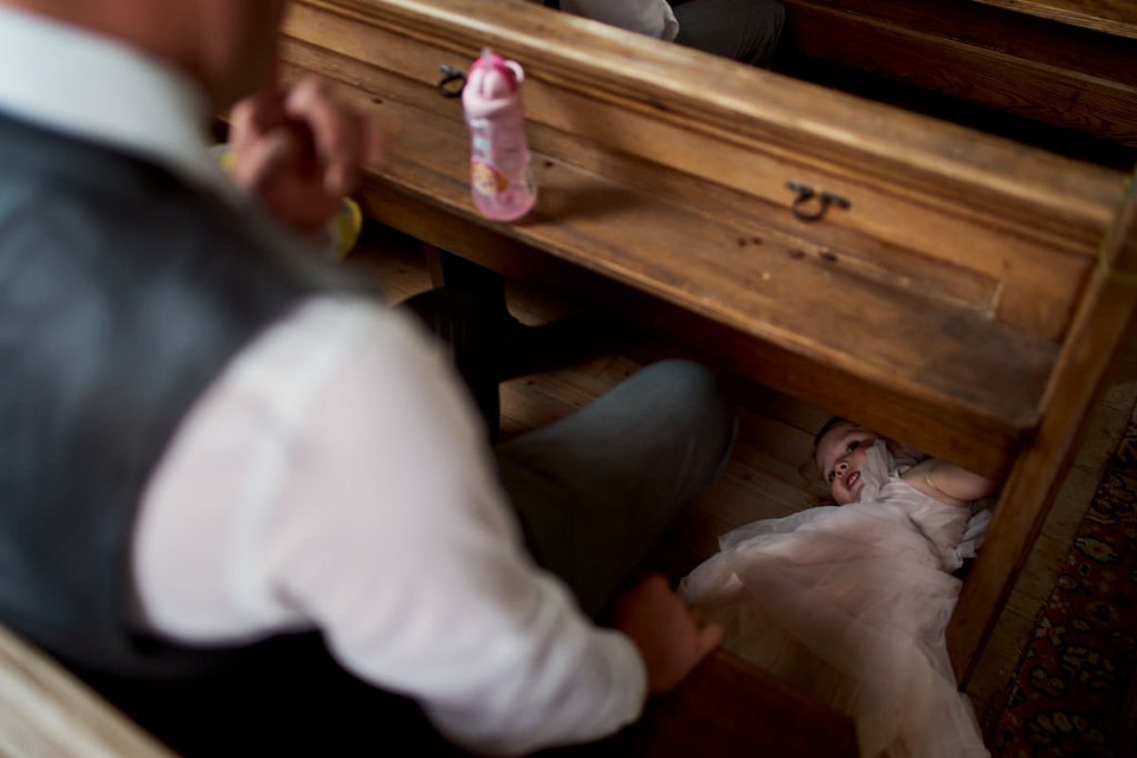 little girl hiding under pews during wedding service