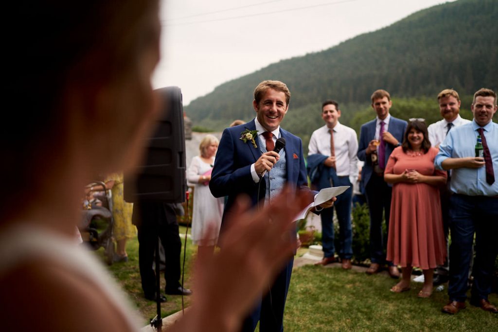groom smiling at bride during his speech