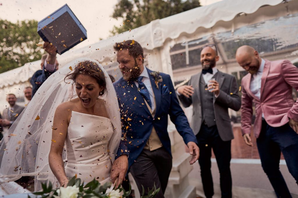 wedding guest throwing confetti at newly wed couple